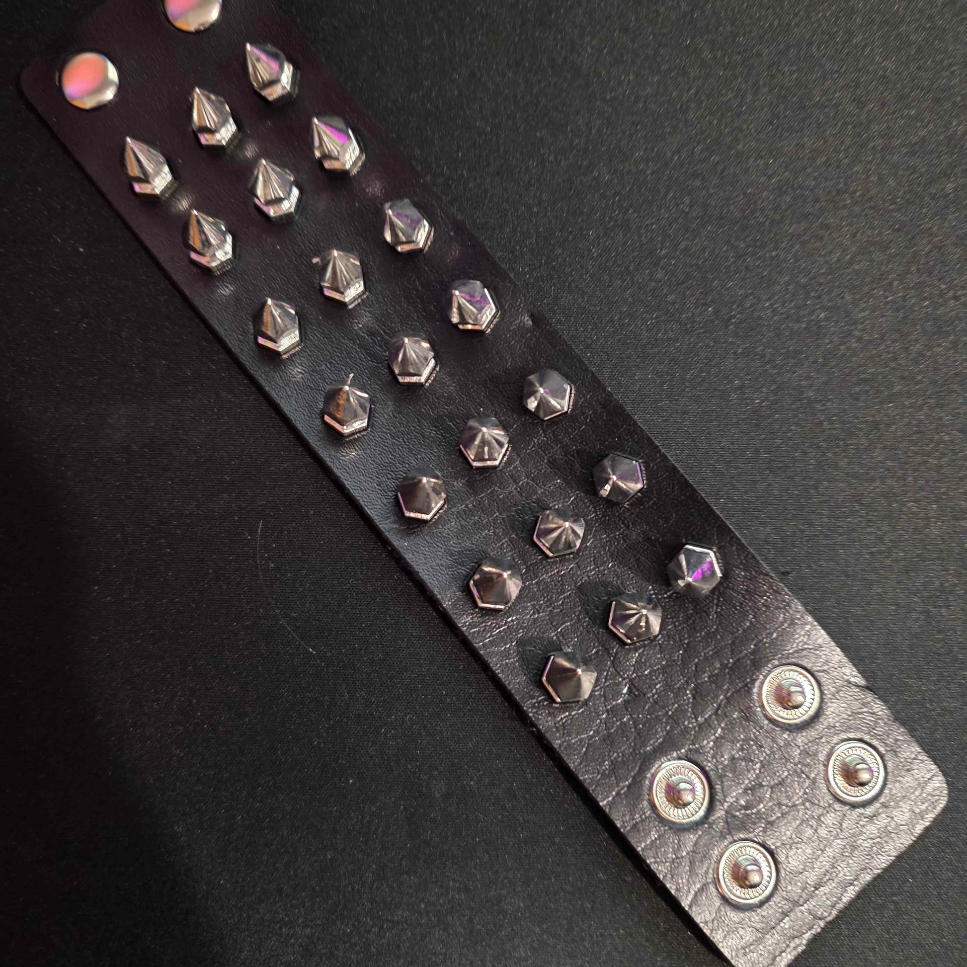Black leather bracelet with silver studs on a dark background