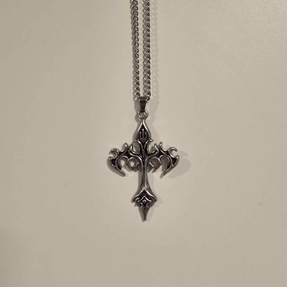 Silver cross pendant necklace on a light gray background