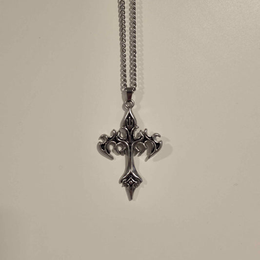Silver cross pendant necklace on a light gray background