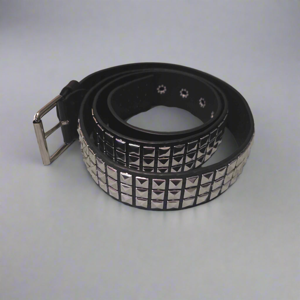 Black studded belt on a gray surface with clothes in the background