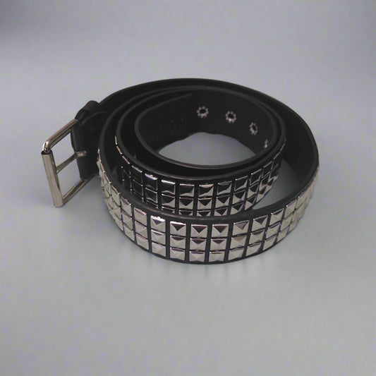 Black studded belt on a gray surface with clothes in the background